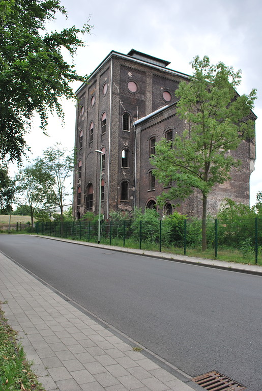 Der denkmalgeschützte Malakoffturm über Schacht I der Zeche Rheinpreußen ist mit einem Teil der Schachthalle erhalten geblieben. Die Giebelinschrift verweist auf das Jahr 1879, als die Förderung begann (2015).