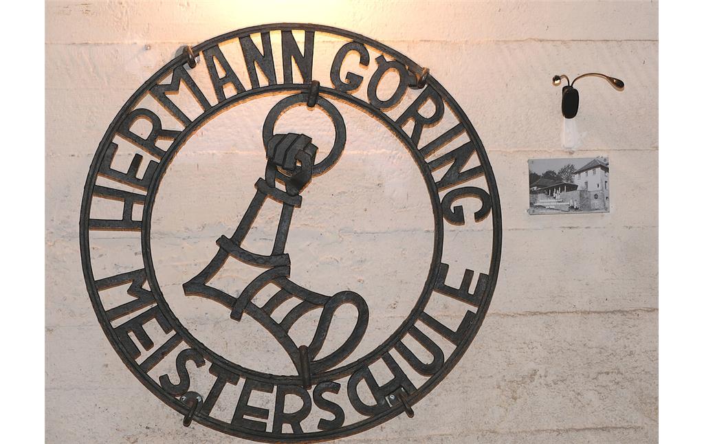 Bild 32: Das schmiedeeiserne Emblem Hermann Görings mit dem Namen der "Hermann Göring Meisterschule" im Luftschutzkeller des Gebäudes in Kronenburg (2022).