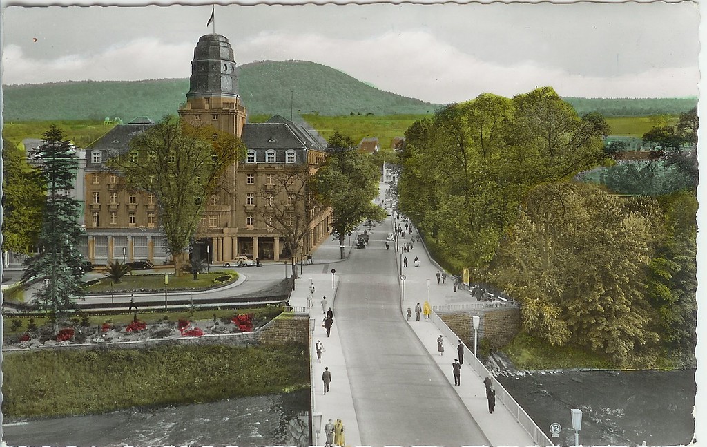 Der Kurpark Bad Neuenahr auf einer historischen Postkarte um 1960. Blick auf die Ahrbrücke und die Kurgartenstraße, rechts davon beginnt der zentrale Bereich des heutigen Kurparks