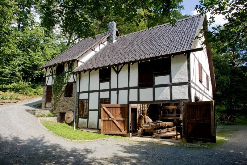 Das in den Hang gebaute Fachwerkgebäude der Gaderother Mühle mit offenem Holztor (2011).