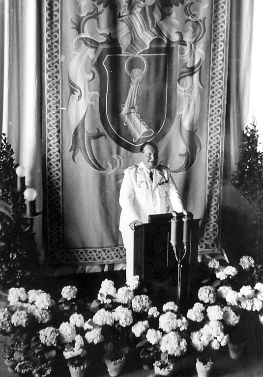 Bild 33: Hermann Göring am 8. Juni 1938 bei der Eröffnungsrede der "Meisterschule" in Kronenburg. Hinter ihm das Hauswappen seiner Familie auf dem Wandteppich.