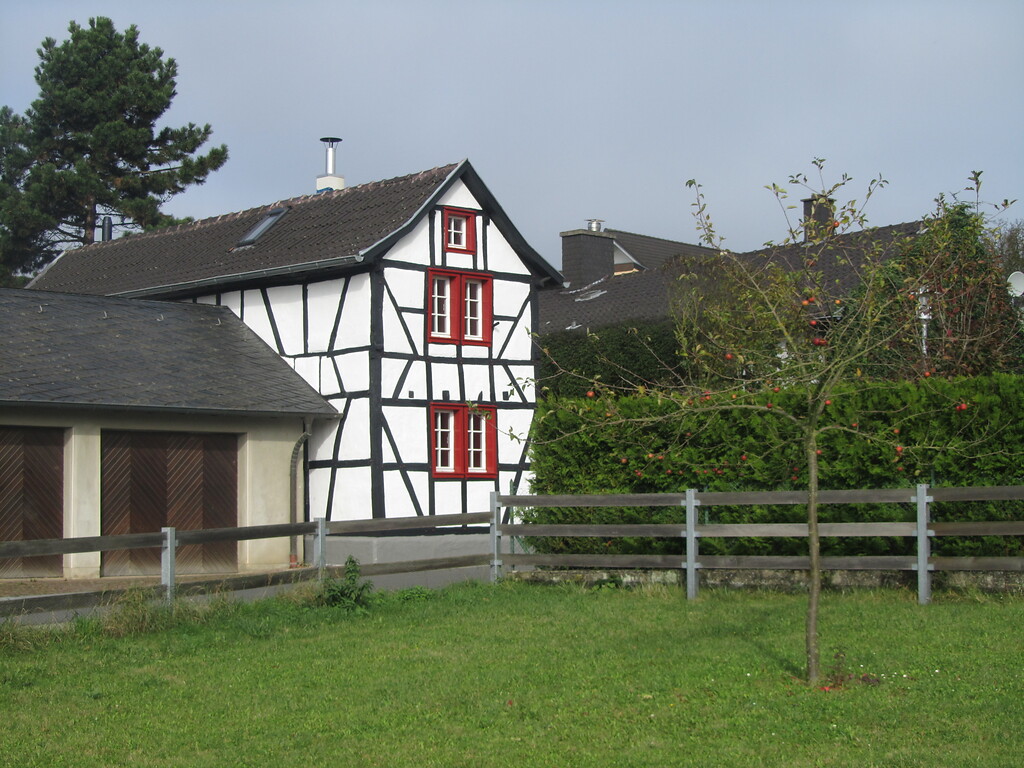 Das zweigeschossige giebelständige Fachwerkwohnhaus hat rot umrahmte Sprossenfenster und ein Satteldach (2014)