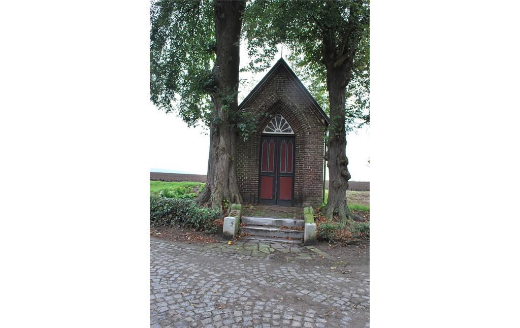 Westlich vor dem Meerhof steht. flankiert von zwei hohen, alten Bäumen, eine kleine Backsteinkapelle mit Spitzbogenfenster und -eingang im neugotischen Stil.