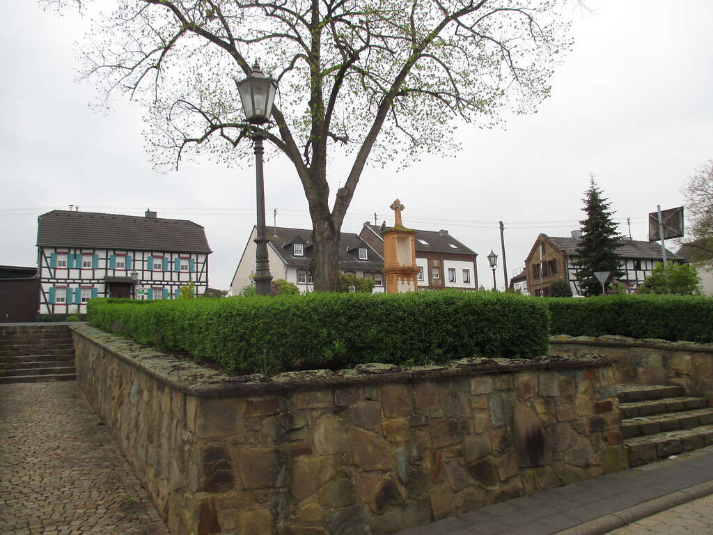 Mit Mauer und Hecke eingefasster Platz mit großem Laubbaum, Treppenaufgang und Wegekreuz in Lommersum (2015)