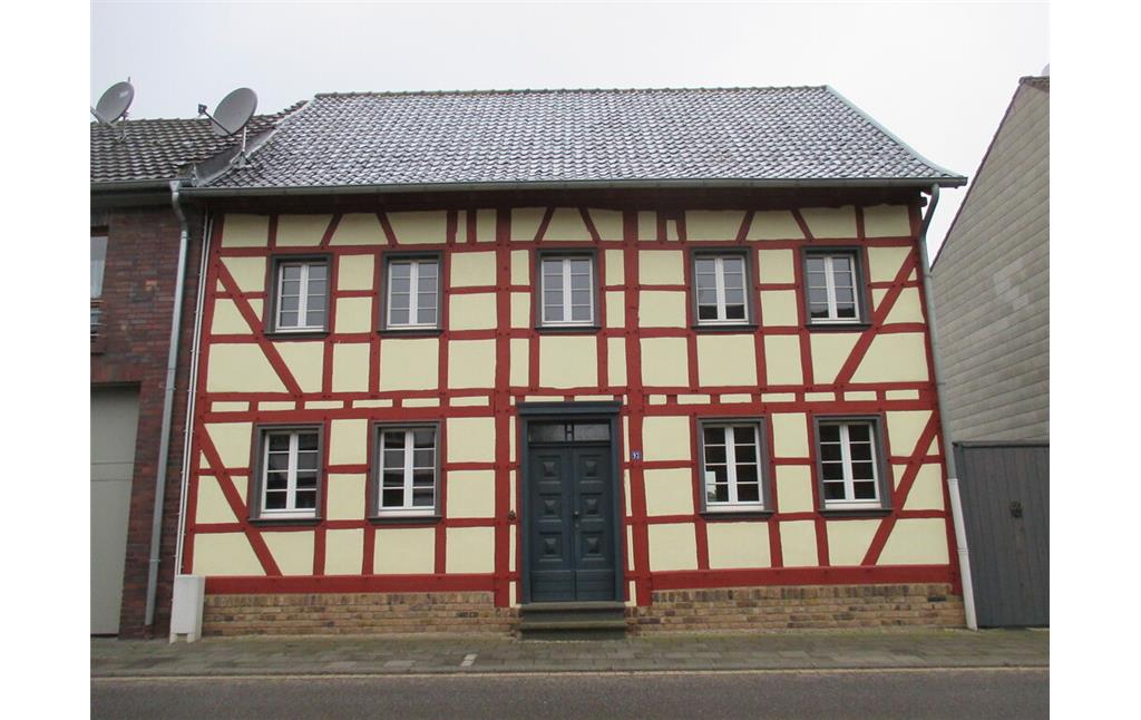 Dieses gelb gestrichene und sehr gepflegte, auf Bruchsteinsockel erbaute Fachwerkhaus in Bürvenich hat rot gestrichene Balken. (2014)