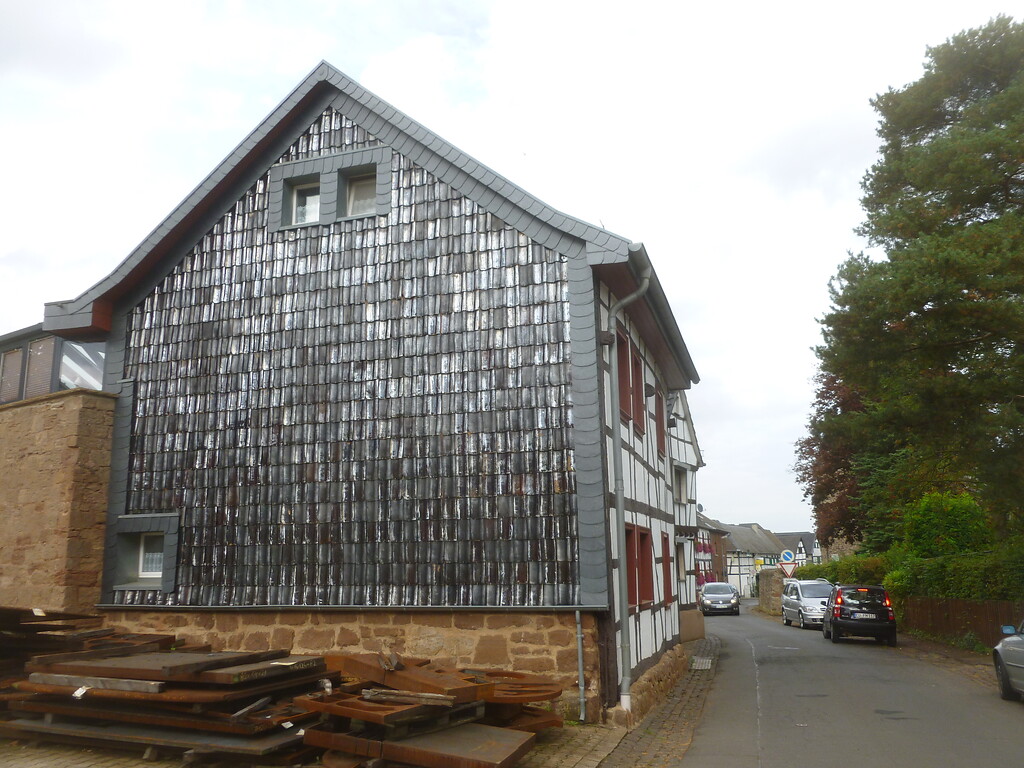 Die Wetterseite dieses Fachwerkhauses in Hostel ist mit Dachpfannen geschützt und mit Schiefer eingefasst. (2014)
