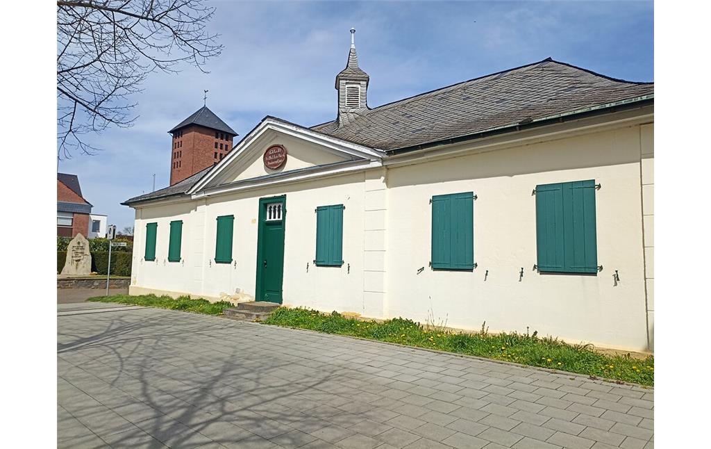 Die ehemalige Schule Delhoven wurde 1825 errichtet. Der eingeschossige klassizistische Winkelbau hat einen Dreieckgiebel und einen Dachreiter (Türmchen), in dem die Schulglocke hing (2022).