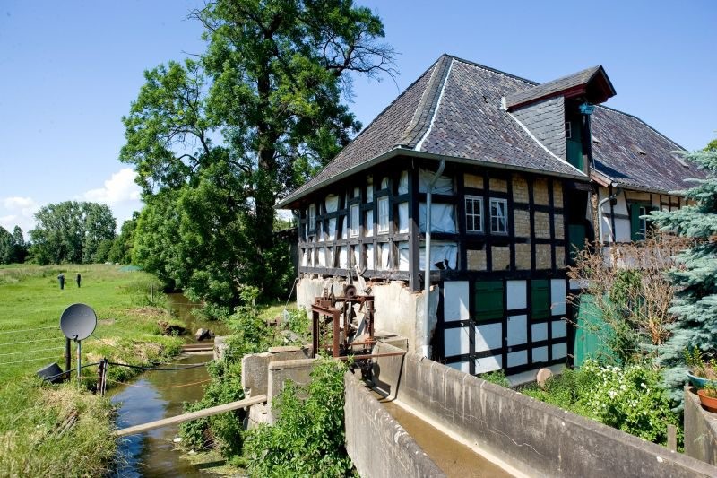 Das Fachwerkgebäude der Bliesheimer Mühle mit Mühlgraben und Zulauf