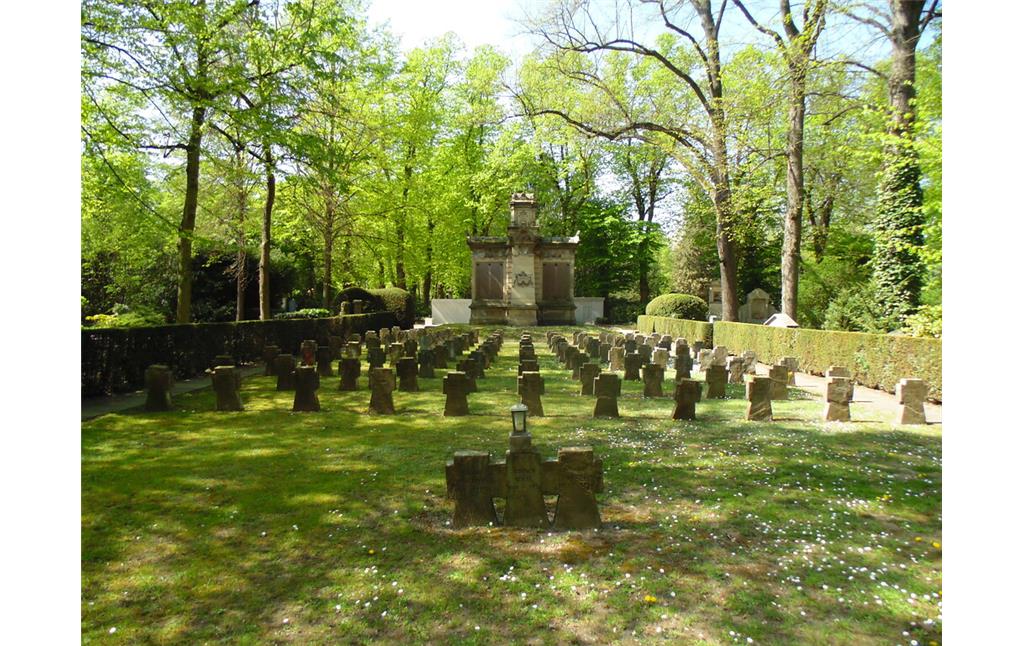 Gräberreihen für Gefallene des Zweiten Weltkriegs auf dem Kriegsgräberfeld V1 auf dem Melatenfriedhof in Köln-Lindenthal. Im Hintergrund ist das Kriegerdenkmal und Soldaten-Grabmal von 1870/71 zu sehen (2020).