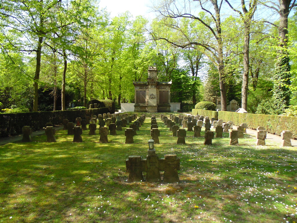 Gräberreihen für Gefallene des Zweiten Weltkriegs auf dem Kriegsgräberfeld V1 auf dem Melatenfriedhof in Köln-Lindenthal. Im Hintergrund ist das Kriegerdenkmal und Soldaten-Grabmal von 1870/71 zu sehen (2020).