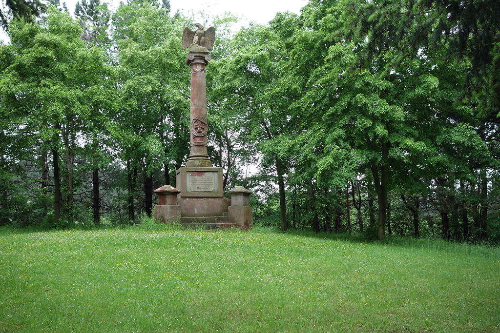 Das mehrere Meter hohe Kriegerdenkmal aus Sandstein steht auf einer Lichtung im Wald oberhalb von Bürvenich. Der getreppte Sockel trägt eine Säule, die von einem Adler gekrönt wird. Das Denkmal wurde 1887 errichtet (2016).
