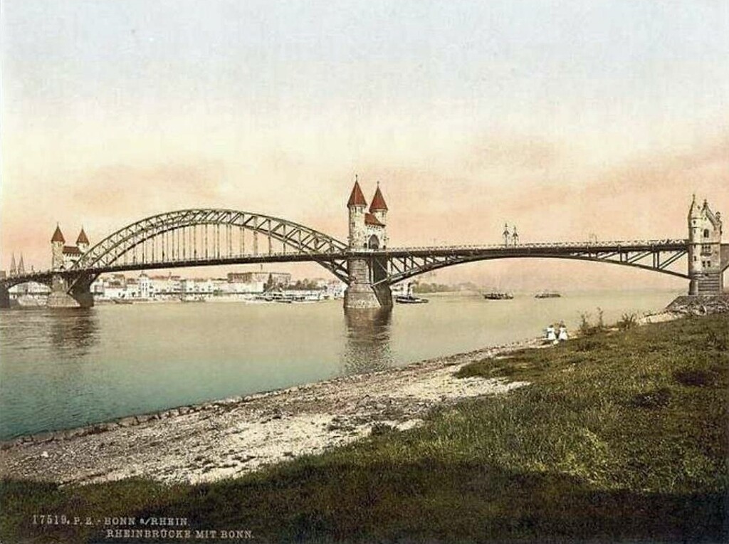 Die undatierte Farbpostkarte "Bonn a/Rhein, Rheinbrücke mit Bonn" zeigt die Alte Rheinbrücke und das Bonner Flussufer vom Beueler Rheinufer aus.