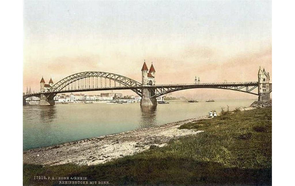 Die undatierte Farbpostkarte "Bonn a/Rhein, Rheinbrücke mit Bonn" zeigt die Alte Rheinbrücke und das Bonner Flussufer vom Beueler Rheinufer aus.