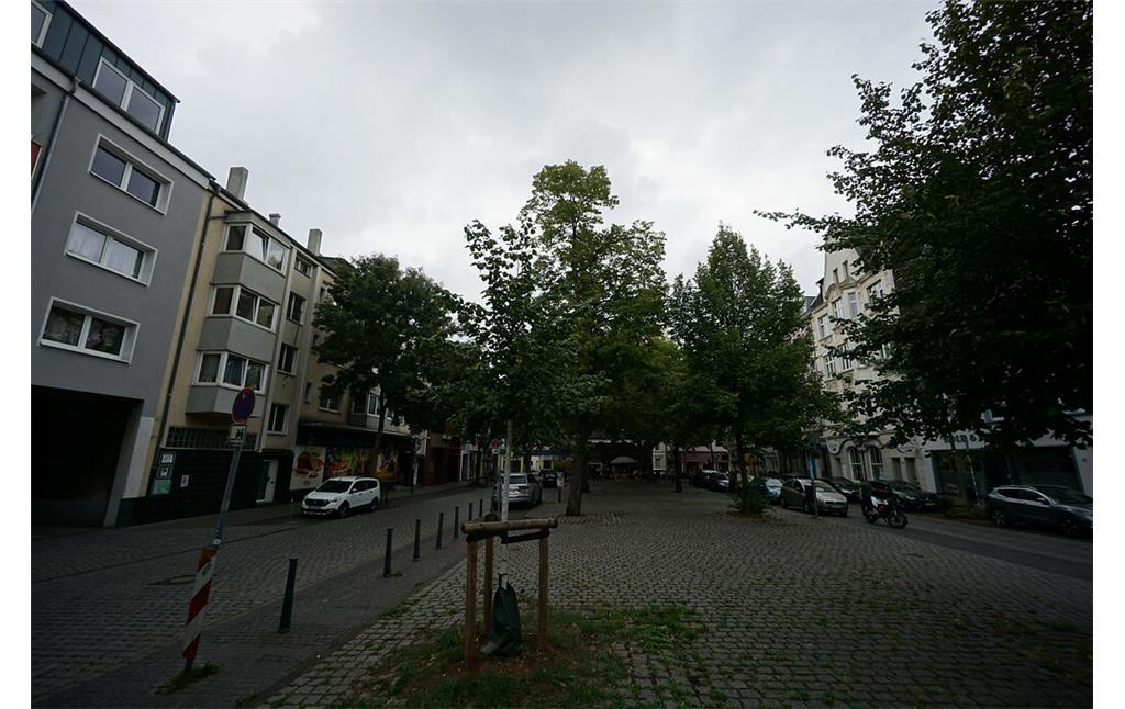 Der gepflasterte Stadtplatz "Neumarkt" wird beidseitig von einer Straße und überwiegend viergeschossigen Häusern umgeben. Wenige Bäume stehen am rand des Platzes (2020).