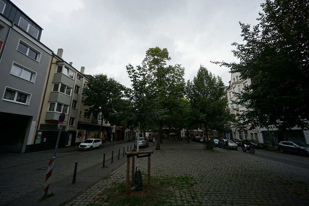 Der gepflasterte Stadtplatz "Neumarkt" wird beidseitig von einer Straße und überwiegend viergeschossigen Häusern umgeben. Wenige Bäume stehen am rand des Platzes (2020).