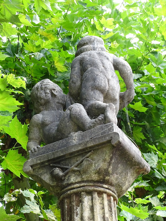 Zwei Figuren (Rückseite) auf einer Säule am Hutmacherbrunnen in Kusel (2018).