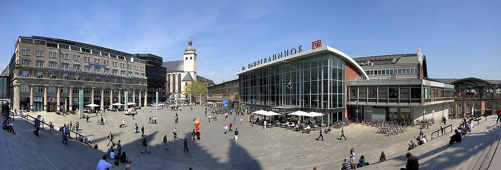 Panoramafoto des Bahnhofvorplatzes in Köln (2010). Von links nach rechts: das "Deichmannhaus" (ehemaliges Bankhaus der "Deichmann & Comp."), St. Mariä Himmelfahrt, der Hauptbahnhof und der alte Wartesaal.