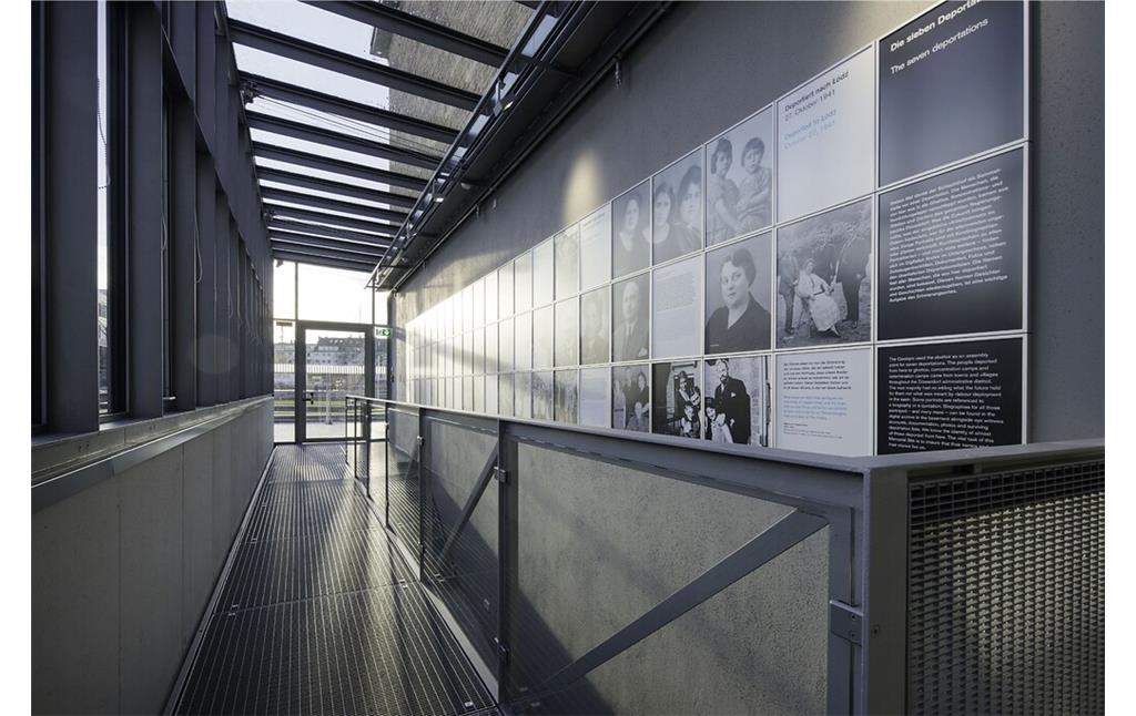 Erinnerungsort Alter Schlachthof in Düsseldorf-Derendorf (2020): Über dem früheren Viehabstieg ermöglicht ein Gitterrost den Rundgang durch die Ausstellung. An der Wand: Porträts der von hier deportierten Menschen.