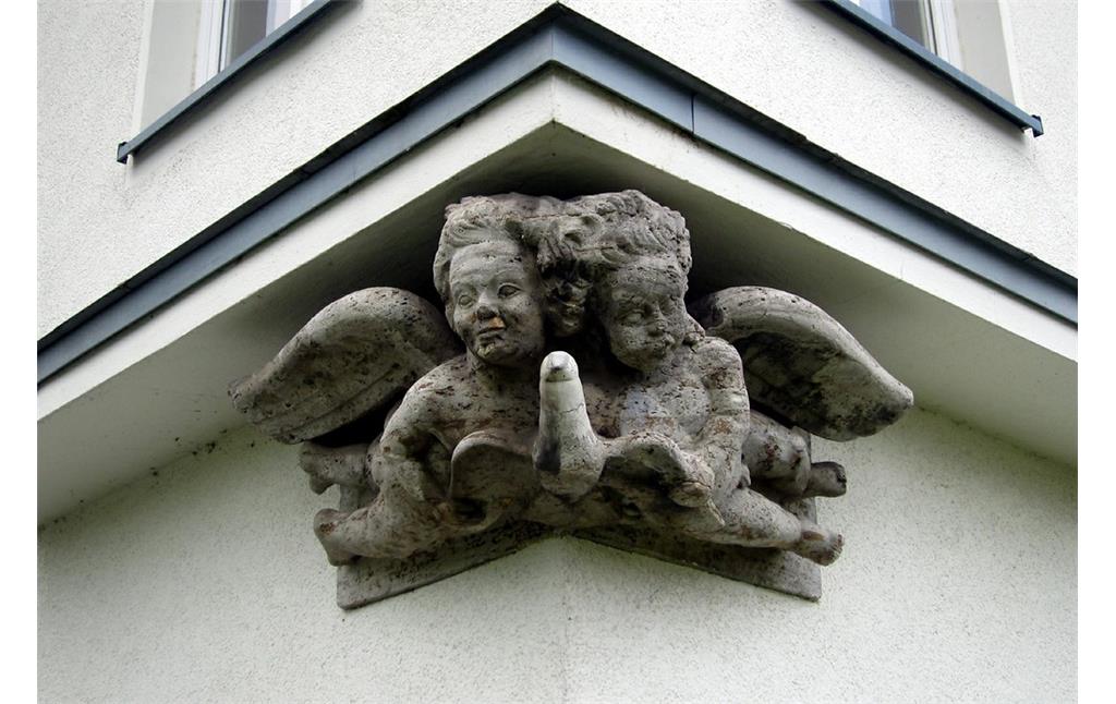 Zwei steinerne Engelfiguren (Putten) mit einer Taube an der nördlichen Ecke der Flugzeughalle II des Flughafens Butzweilerhof (2015).