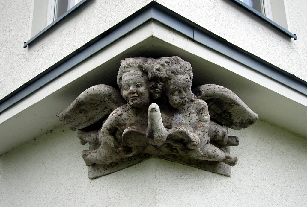Zwei steinerne Engelfiguren (Putten) mit einer Taube an der nördlichen Ecke der Flugzeughalle II des Flughafens Butzweilerhof (2015).