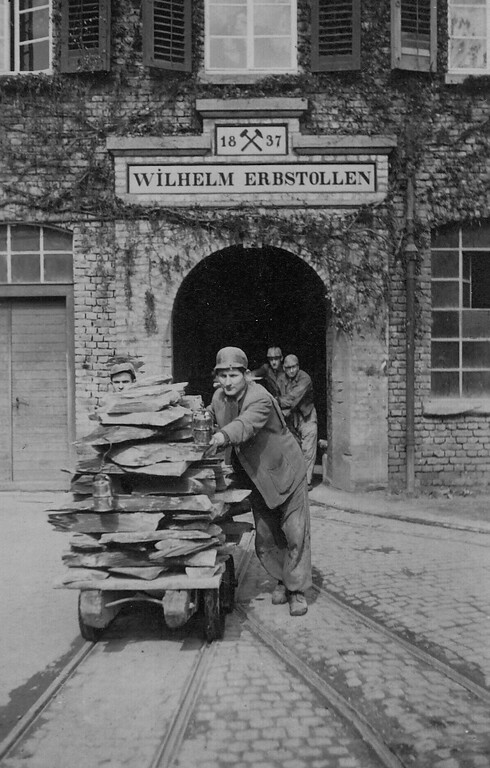 Dachschieferbergbau in Kaub: Arbeiter und Plattenwagen mit bergfeuchtem Schiefer an dem Mundloch auf dem Weg zur Säge (1920er Jahre)