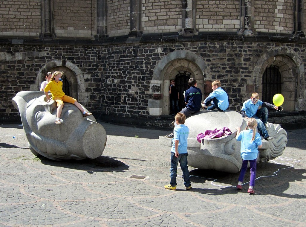 Spielende Kinder an den Kopfplastiken der Märtyrer Cassius und Florentius am Bonner Cassiusstift (Ostseite des Kirchengebäudes, 2011).