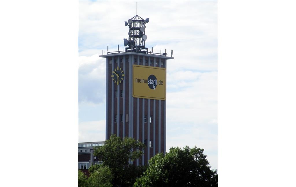 Blick vom Buisdorfer Siegwehr aus auf den oberen Teil des 55 Meter hohen Turms der früheren Zellwolle-Werke "Phrix" der Rheinischen Zellwolle AG in Siegburg (2016). Zu erkennen sind die Uhr und verschiedene Sende- und Empfangsanlagen auf dem Dach.