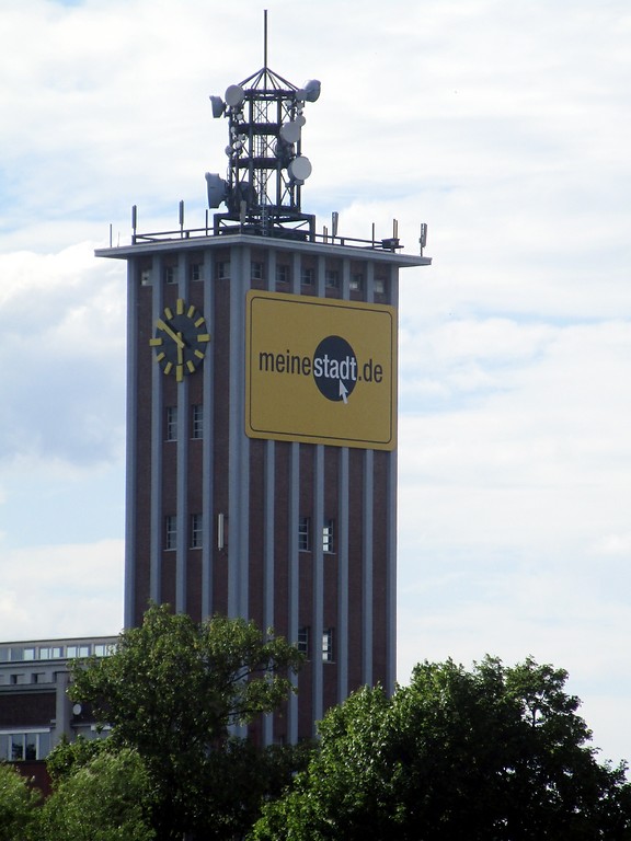 Blick vom Buisdorfer Siegwehr aus auf den oberen Teil des 55 Meter hohen Turms der früheren Zellwolle-Werke "Phrix" der Rheinischen Zellwolle AG in Siegburg (2016). Zu erkennen sind die Uhr und verschiedene Sende- und Empfangsanlagen auf dem Dach.