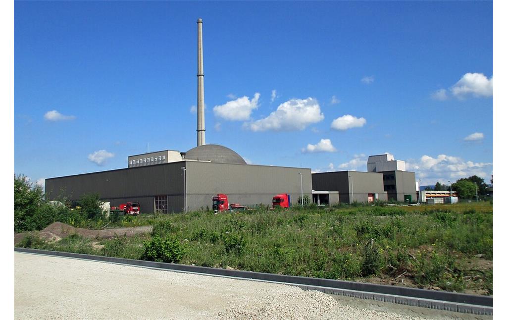 Blick von Süden her auf das Reaktorgebäude und den Abluftkamin des stillgelegten Kernkraftwerks Mülheim-Kärlich, davor befinden sich Betriebsgebäude einer Autokran-Firma (2020).