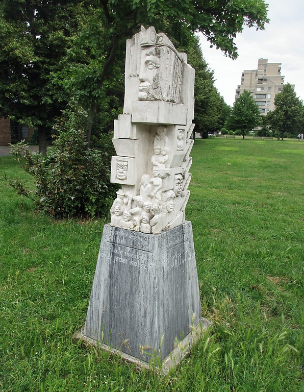 Skulptur mit der Sockelinschrift "Nicht alle sind deutsch aber jeder kölsch" in verschiedenen Sprachen an der Oxforder Passage in Köln-Chorweiler (2018).