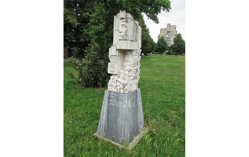 Skulptur mit der Sockelinschrift "Nicht alle sind deutsch aber jeder kölsch" in verschiedenen Sprachen an der Oxforder Passage in Köln-Chorweiler (2018).