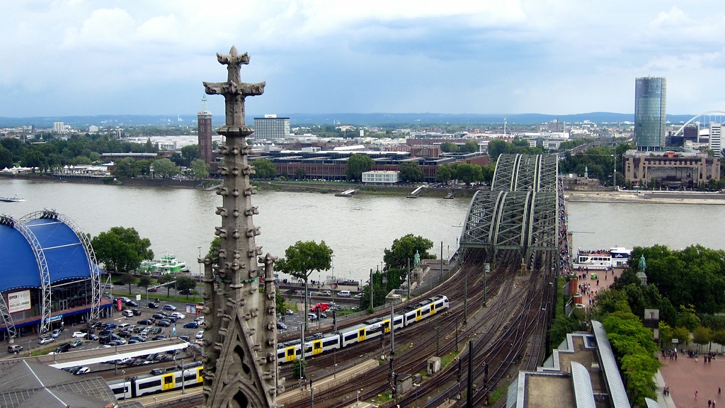 Blick über den Rhein auf den Kölner Stadtteil Deutz im Bereich des Messegeländes, rechts im Bild das Hochhaus Kölntriangle, davor die Hohenzollernbrücke über den Rhein (Ansicht vom Dach des Kölner Doms aus, 2014)