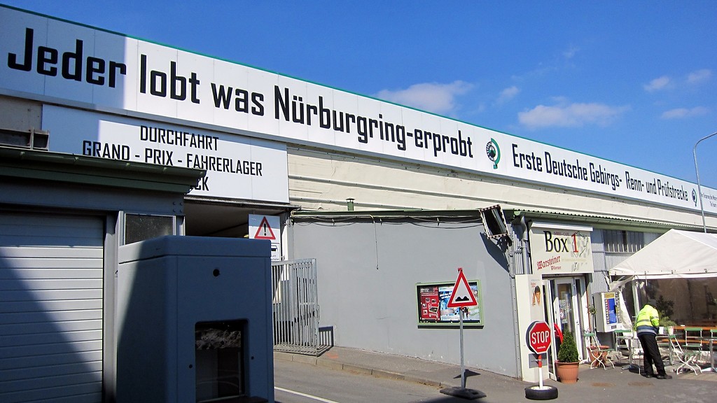 Teil des alten Fahrerlagers am Nürburgring und die Einfahrt zum neuen Fahrerlager, darüber der Werbespruch von 1935 "Jeder lobt was Nürburgring erprobt" (2013)