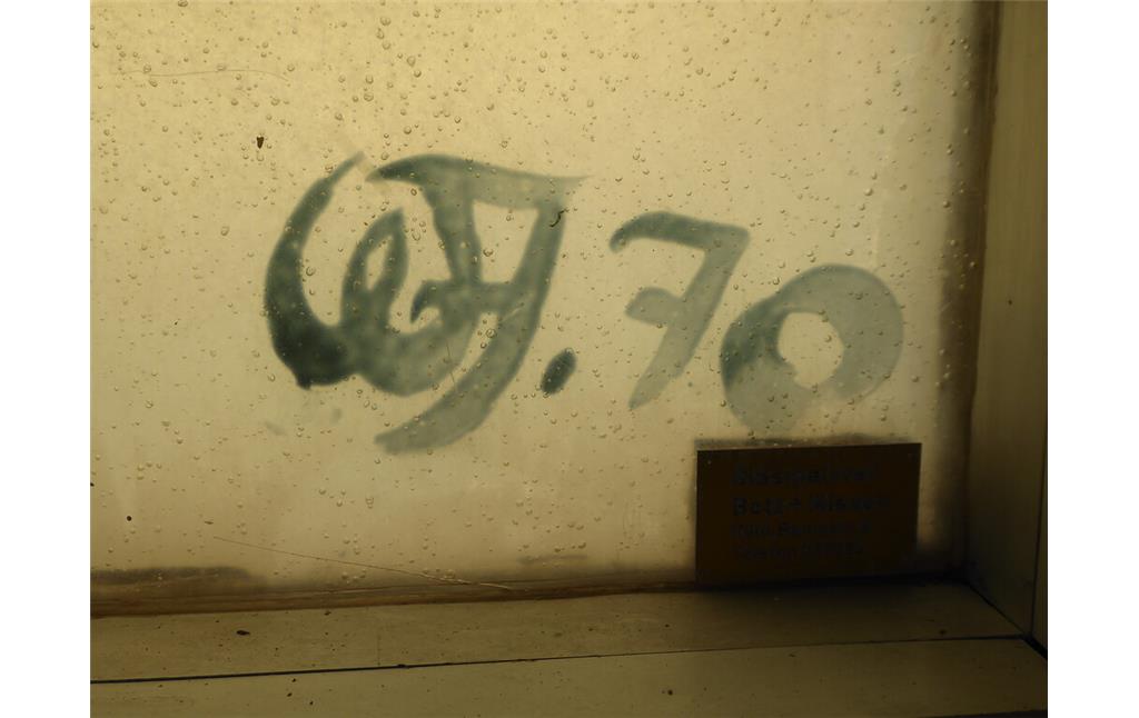 Signatur (WJ.70) des Künstlers Wilhelm Jungeherz auf dem Kunstharzfenster des Viktoriabads in Bonn.(2021)