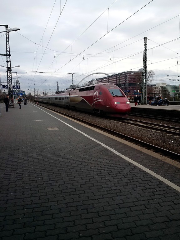 Ein durch den Bahnhof Köln Messe/Deutz fahrender Thalys-Hochgeschwindigkeitszug sowie Bahnsteige und Gleiskörper (2015).