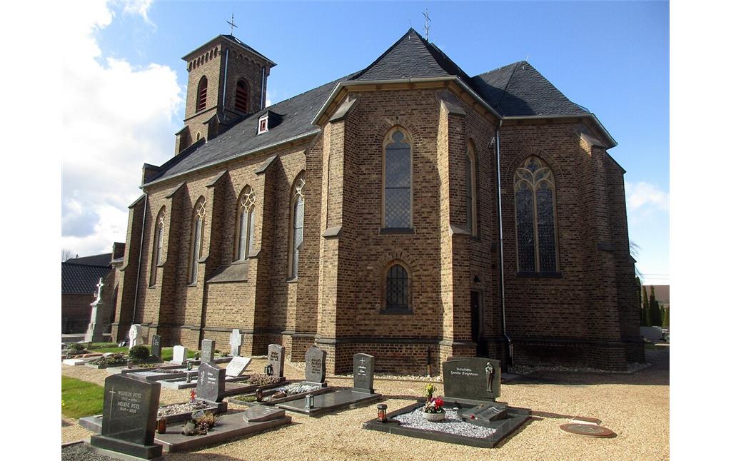 Blick auf die Südseite der katholischen Pfarrkirche Sankt Johann Baptist mit dem umgebenden Friedhof in Vettweiß-Sievernich (2021).