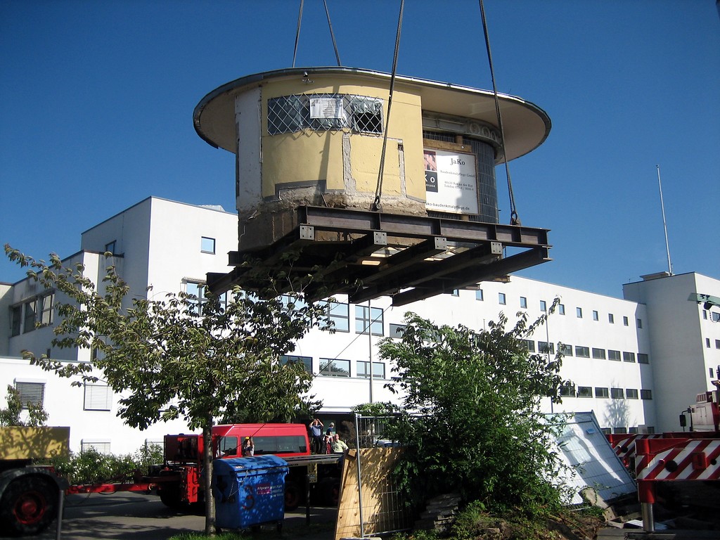 Ein Kran hebt das denkmalgeschützte "Bundesbüdchen"  einen Kiosk im Bonner Regierungsviertel  an, um diesen zu seinem Zwischenlager, einem Bauhof in Hersel, transportieren zu können (2006).