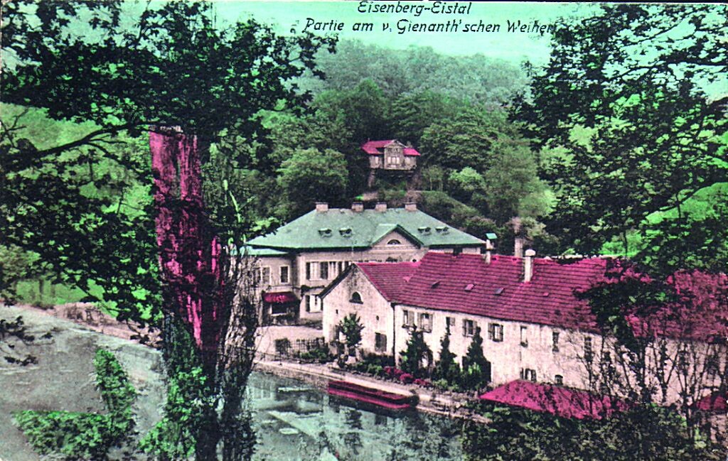 Historische Postkarte mit Blick schräg über den Weiher auf das Herrenhaus der Familie Gienanth (links) und die langgestreckte Häuserzeile mit den Arbeiterwohnungen (um 1910)