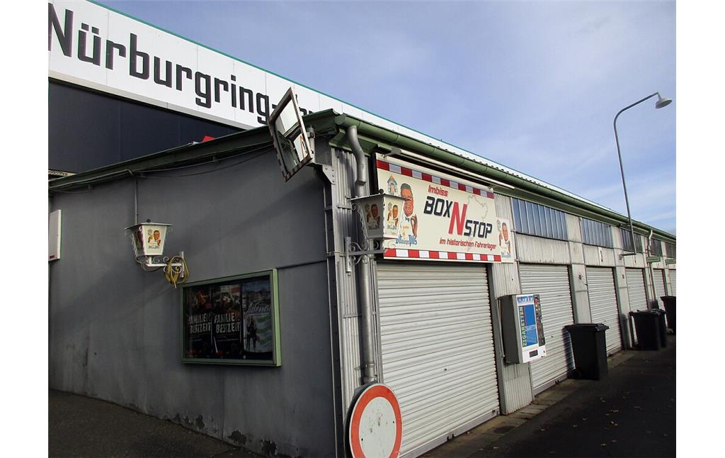Historisches Fahrerlager am Nürburgring: Blick über die nordwestliche Reihe der Garagenboxen mit dem "Imbiss BoxNStop im historischen Fahrerlager" in Box Nr. 1 (2020).