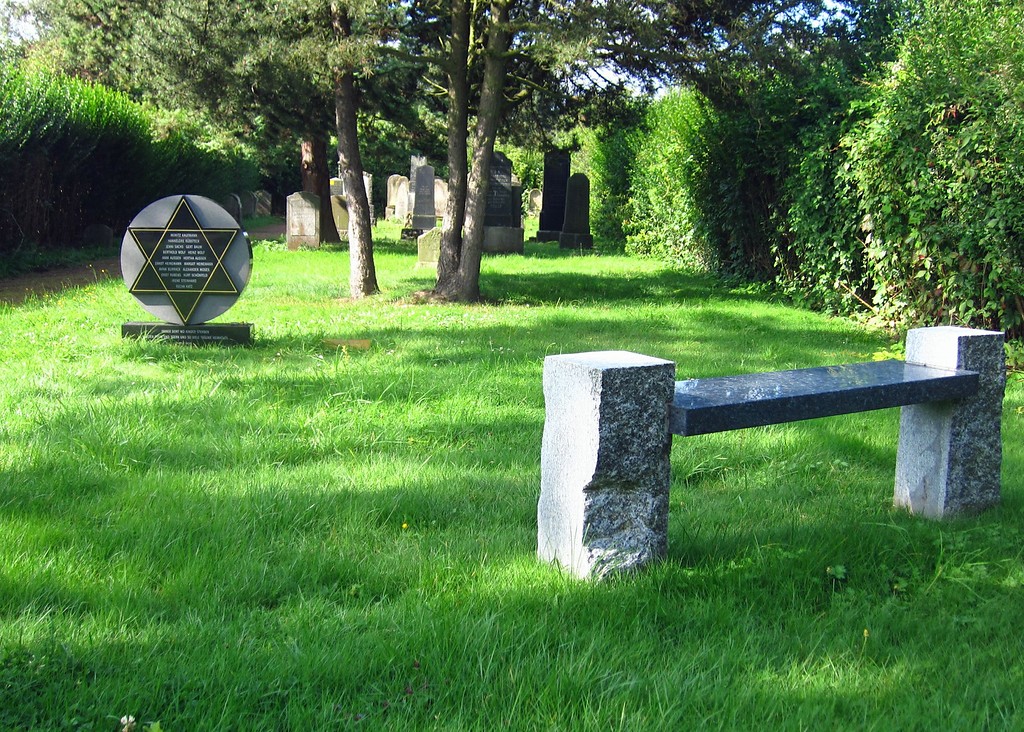Der jüdische Friedhof in Wevelinghoven mit einer Bank und einem Gedenkstein im Vordergrund (2014).