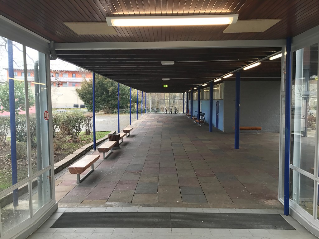 Weiterbildungskolleg Bonn, überdachtes Schulgelände mit Sitzbänken und Toiletteneingängen (rechts) (2017)