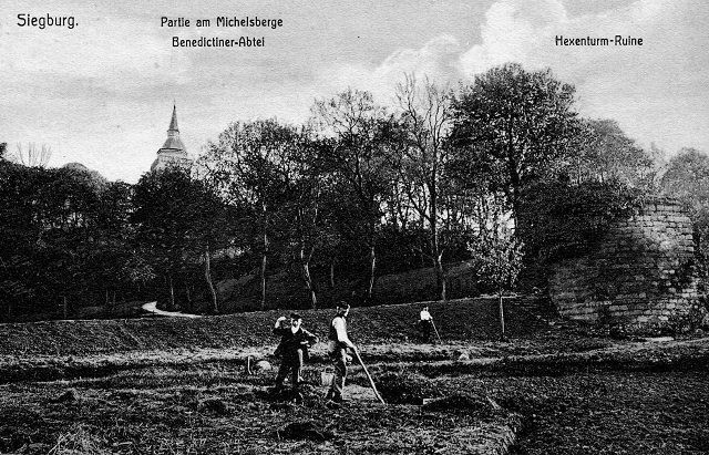 Eine historische Postkarte von 1909 zeigt rechts im Bild die Ruine des Siegburger Hexenturms, im Hintergrund der Turm der Abteikirche Sankt Michael.