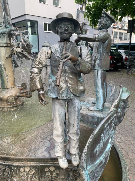 Der Kölner Musikant Arnold Wenger (1836-1902), bekannt als "Fleuten-Arnöldche", dargestellt am Karl-Berbuer-Brunnen auf dem Karl-Berbuer-Platz in Köln-Altstadt-Süd (2022).