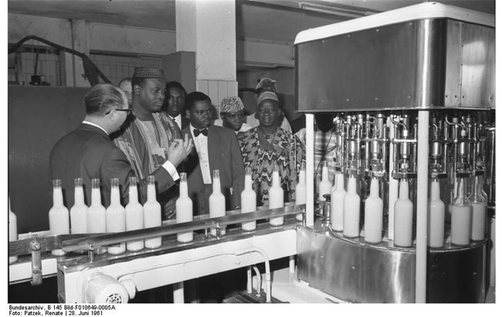 Historische Aufnahme von 1961: Eine Parlaments-Delegation aus der Republik Niger bei der Besichtigung der Firma "Verpoorten" in Bonn, im Bildvordergrund eine Flaschen-Abfüllanlage.