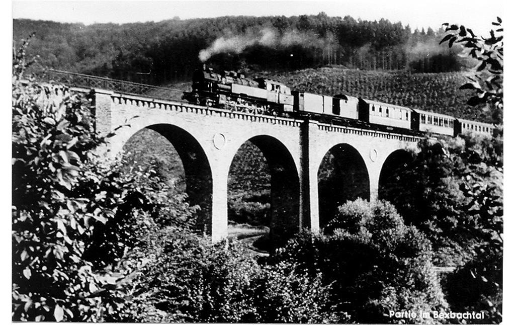 Historische Aufnahme eines von einer Dampflokomotive gezogenen Personenzuges der Brexbachtalbahn auf einem Viadukt (vermutlich 1920er bis 1940er Jahre).