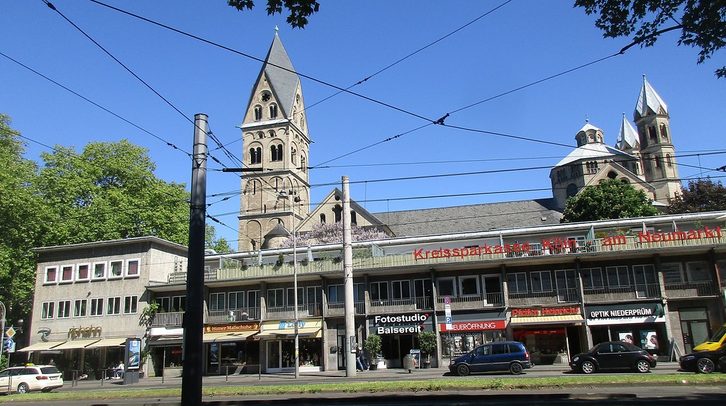 Das Café und Restaurant "Riphahn" (links) und benachbarte Geschäftsgebäude in der Hahnenstraße in Köln-Altstadt-Süd, dahinter das Kollegiatstift Sankt Aposteln in Altstadt-Nord (2019).