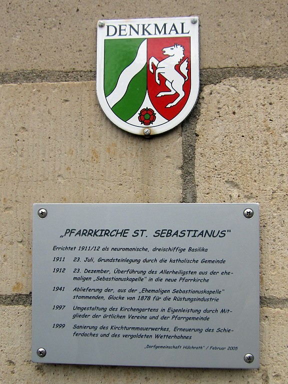 Denkmalplakette und eine Informationstafel an der Sankt Sebastianuskirche in Grevenbroich-Hülchrath (2014).