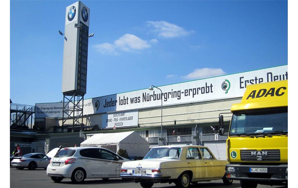 Innenbereich des historischen Fahrerlagers und ein moderner Anzeigeturm mit BMW-Werbung am Nürburgring (2013).