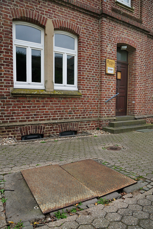 Abgedeckter alter Brunnenschacht vor der Katholischen öffentlichen Bücherei in Dormagen-Gohr (2014)