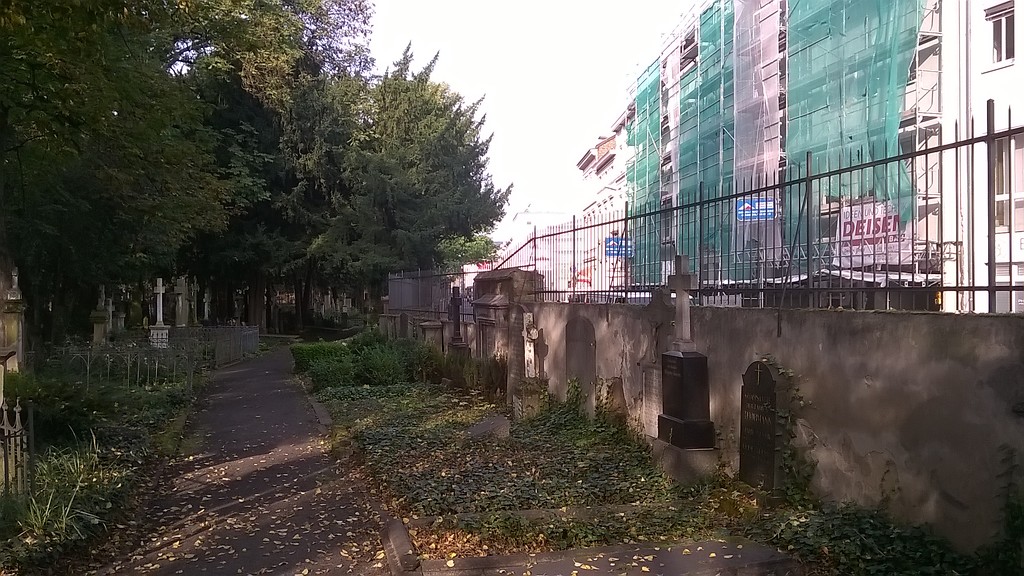 Der nördliche Friedhofsweg mit der nördlichen Friedhofsmauer, Gräbern und Grabmalen auf dem Alten Friedhof in Bonn-Nordstadt.
